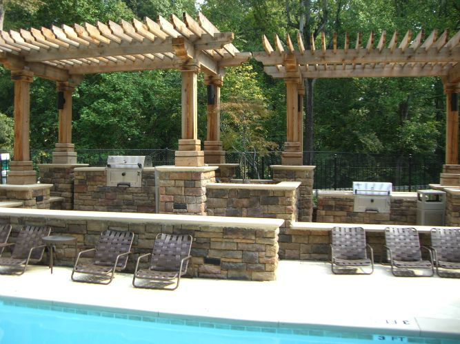 a swimming pool with chairs and a grill under a pergola