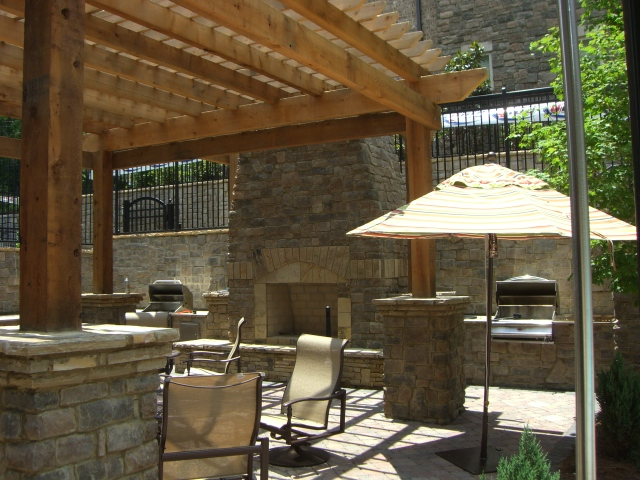 a patio with chairs and umbrellas under a wooden pergola