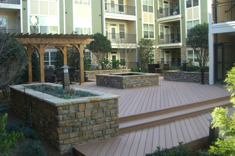 a wooden deck with a pergola and a fire pit in front of a building .
