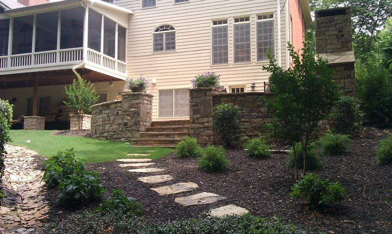 a house with a screened in porch and a stone walkway leading to it .