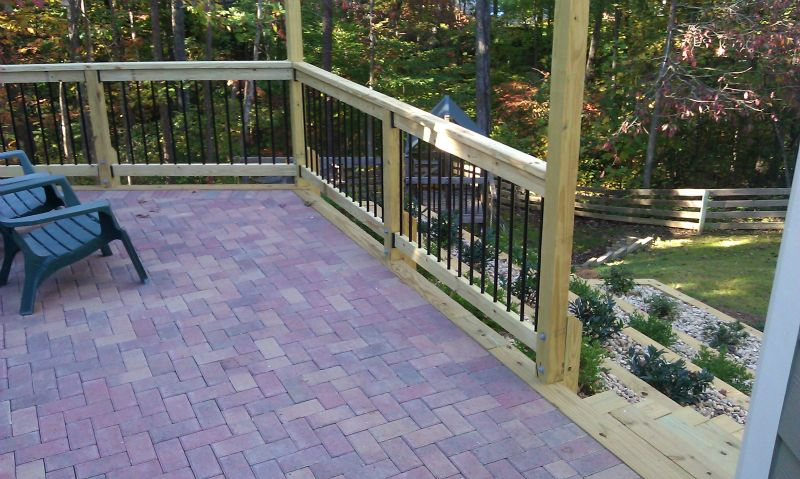 a wooden deck with chairs and a brick floor