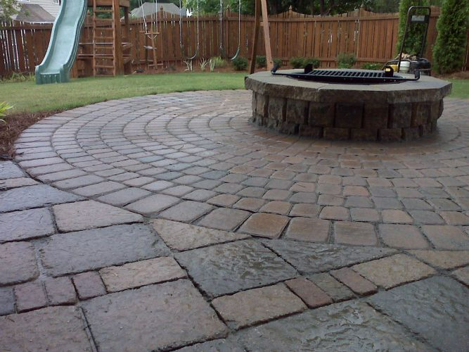 a brick patio with a fire pit and a slide in the background