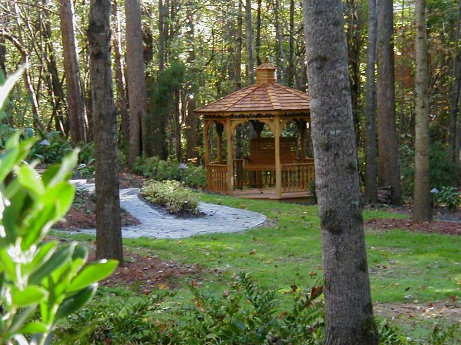 a gazebo in the middle of a forest surrounded by trees