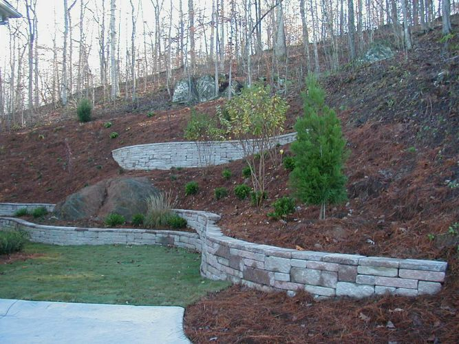 a stone wall is surrounded by trees on a hillside .