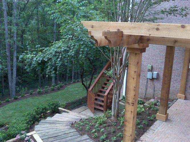 a wooden pergola with stairs leading up to it is in the backyard of a house .