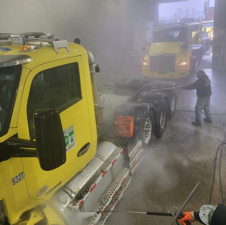 A man is washing a yellow truck