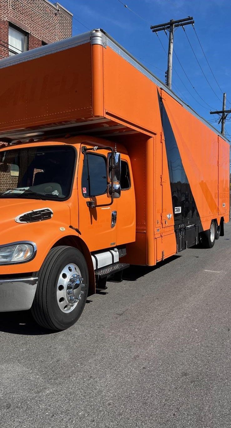 A large orange moving truck is parked on the side of the road