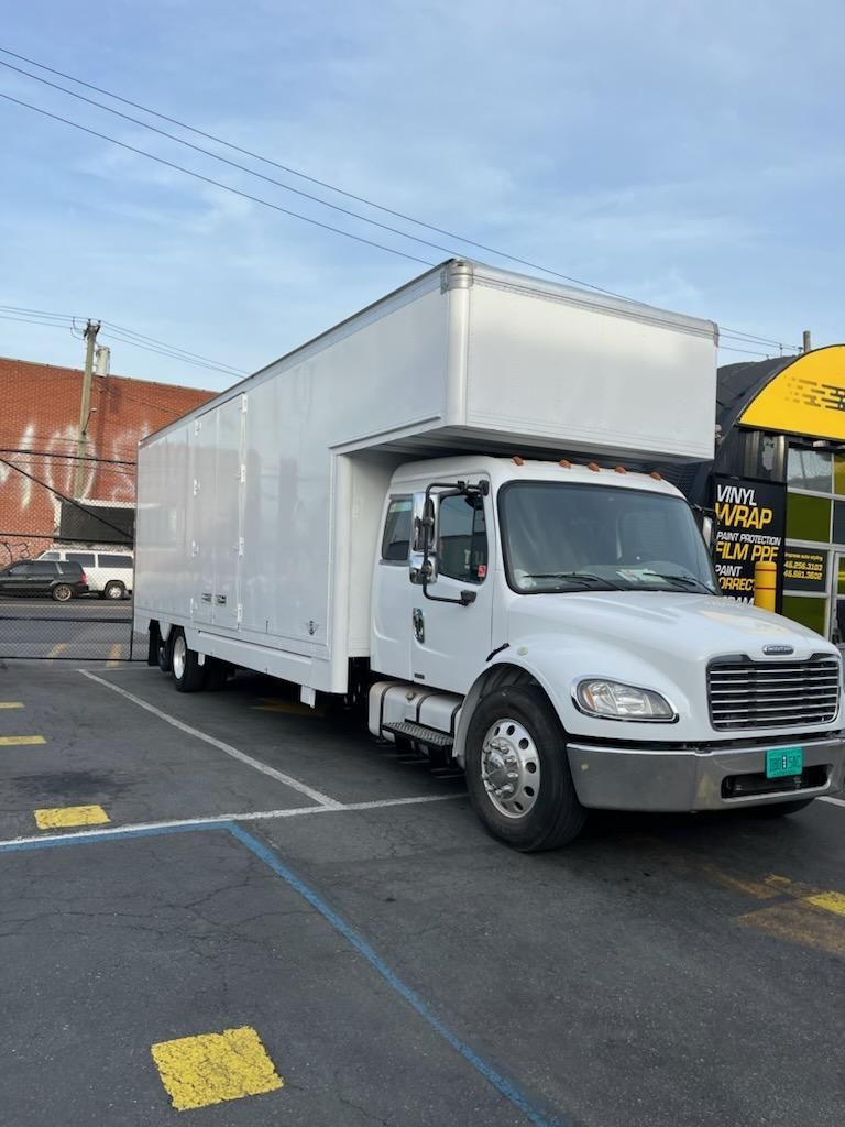 A white moving truck is parked in a parking lot
