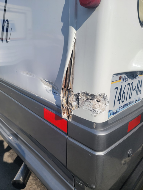 A white van with a scratch on its rear door