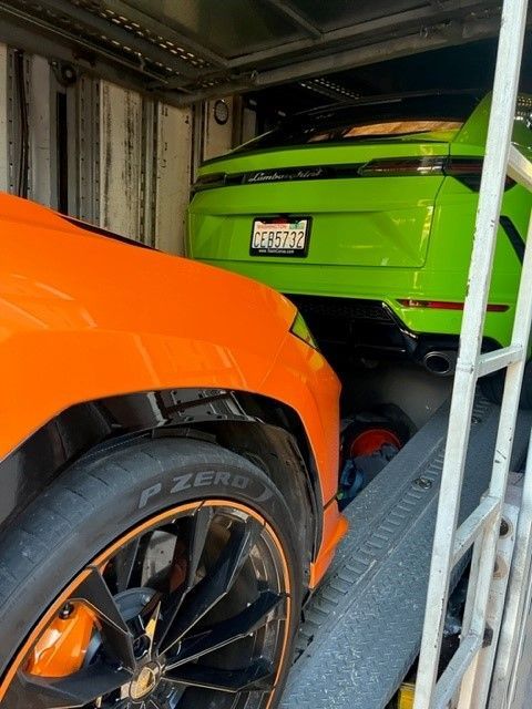 A green Lamborghini is parked next to an orange Lamborghini