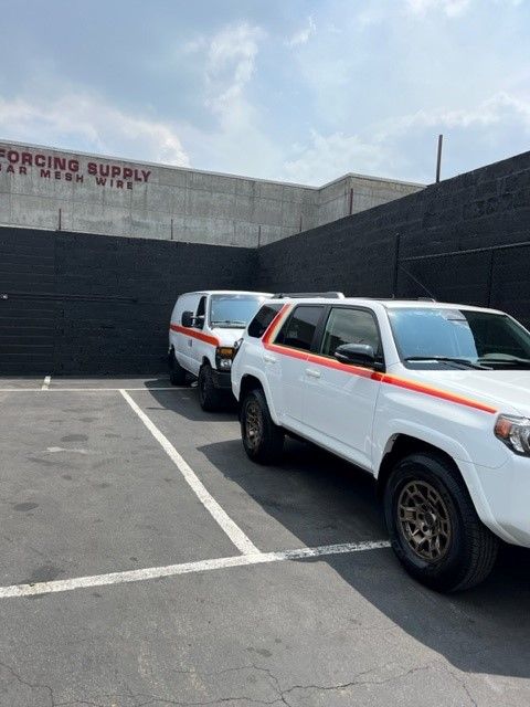 Two white trucks are parked in front of a building