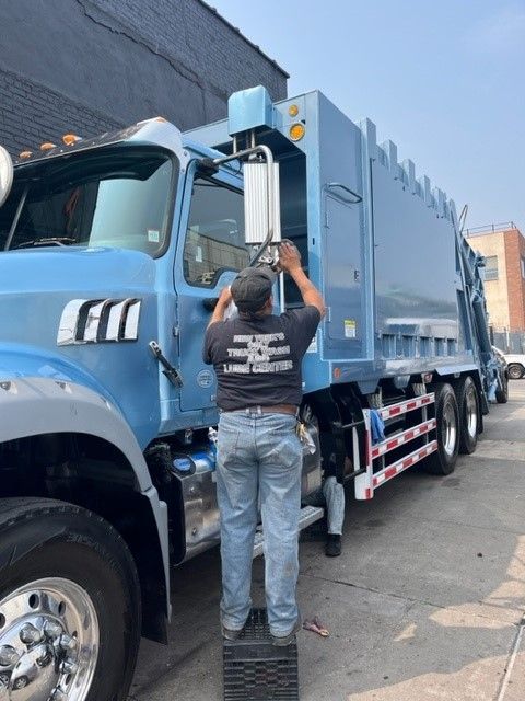 A man is cleaning the blue garbage truck