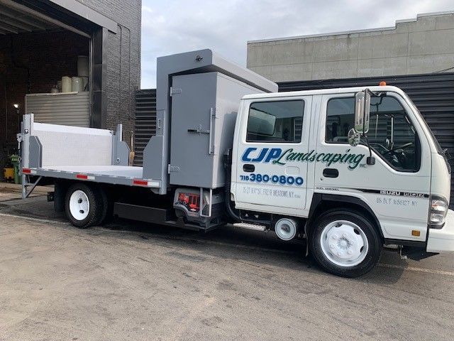 A CJP Landscaping truck is parked in front of a building