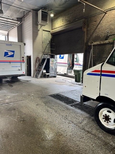 A postal service truck is parked in a garage
