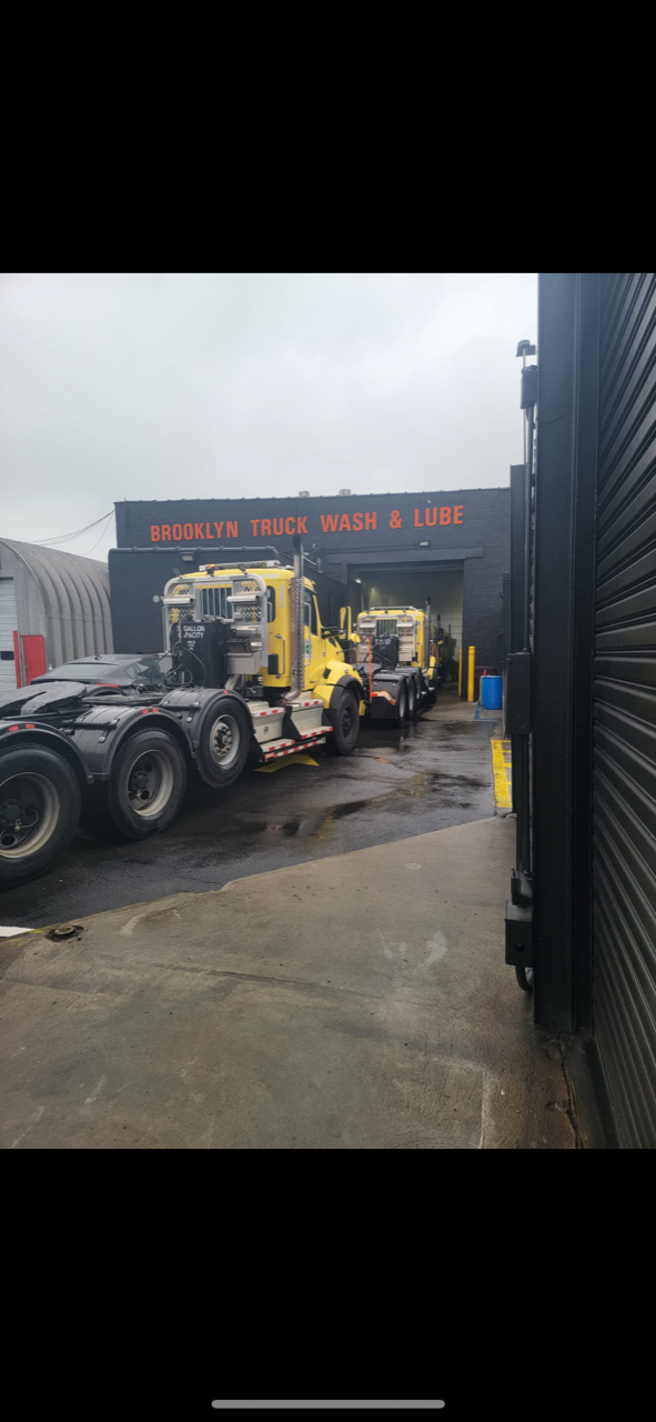 A row of trucks are parked in front of a truck wash