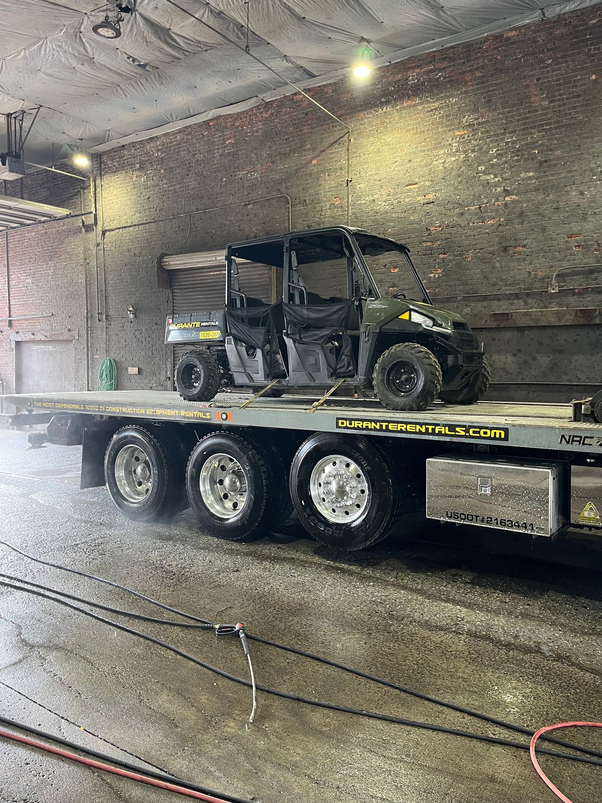 A Polaris ranger is sitting on top of a flatbed truck