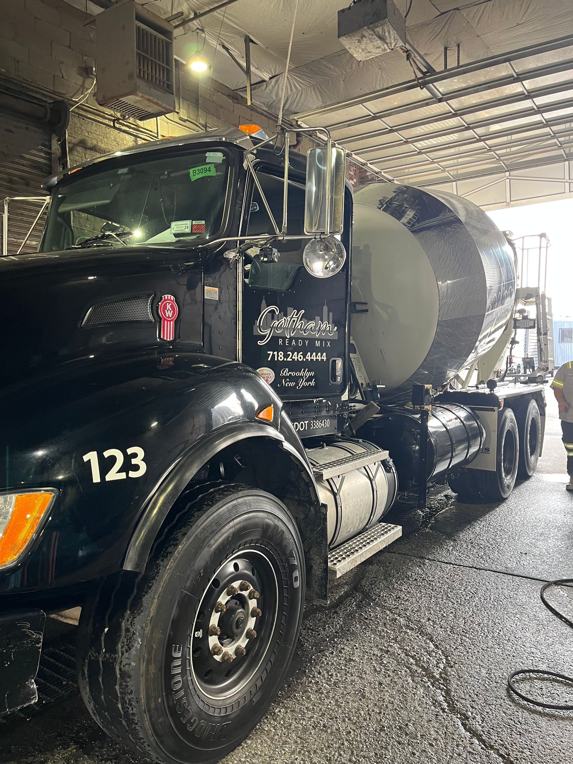 A black concrete mixer truck is being cleaned