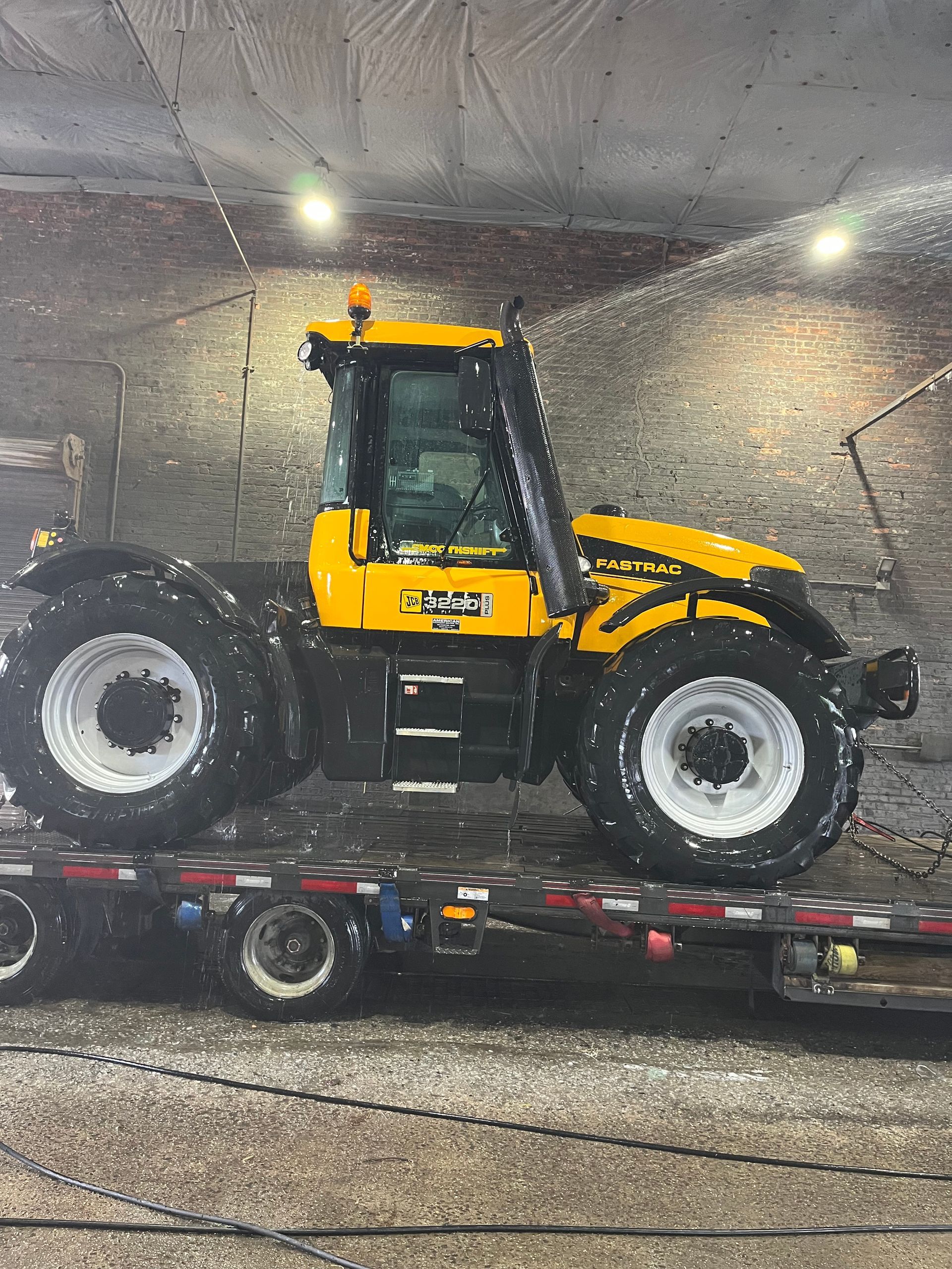 A yellow tractor is sitting on top of a flatbed truck
