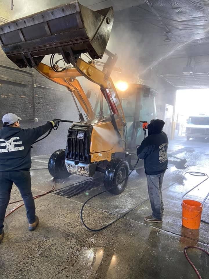 Two men are washing a bulldozer