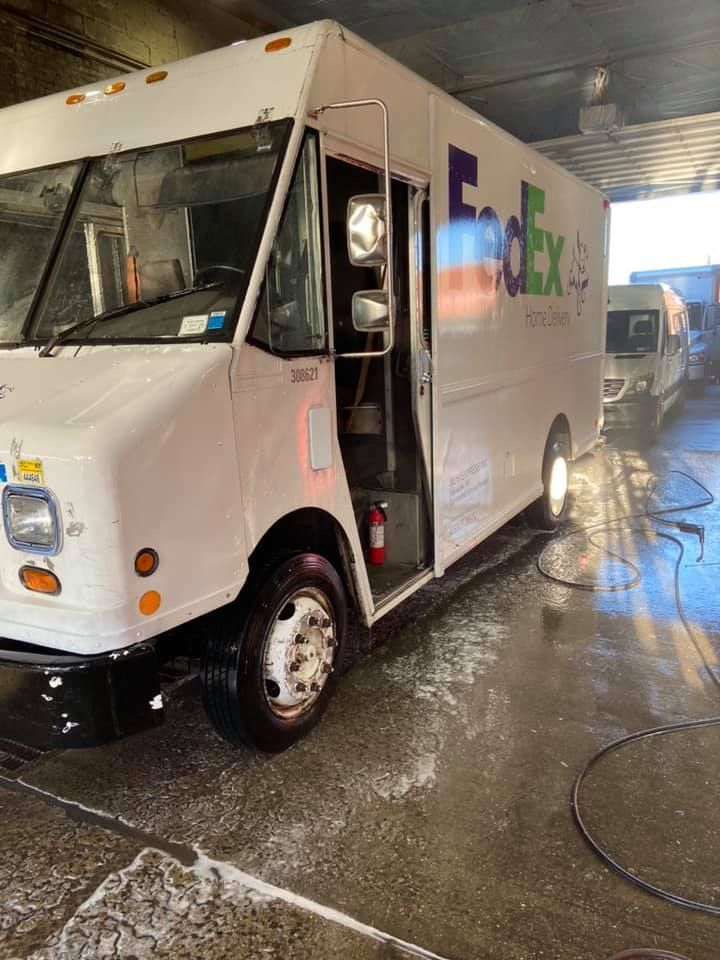 A white FedEx delivery truck is being washed in a garage