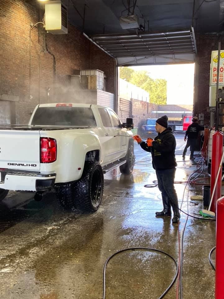 A man using a power washing tool to clean the truck