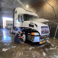 A man is washing a semi truck