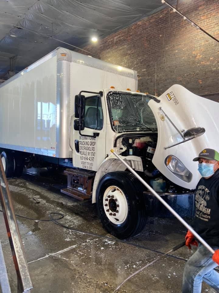 A man is cleaning the hood of a white truck