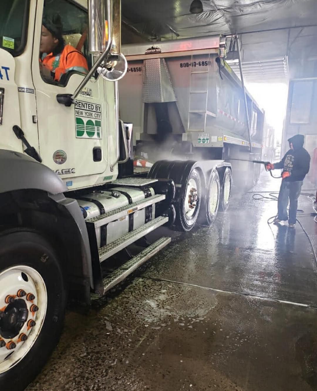 A man is washing a dump truck