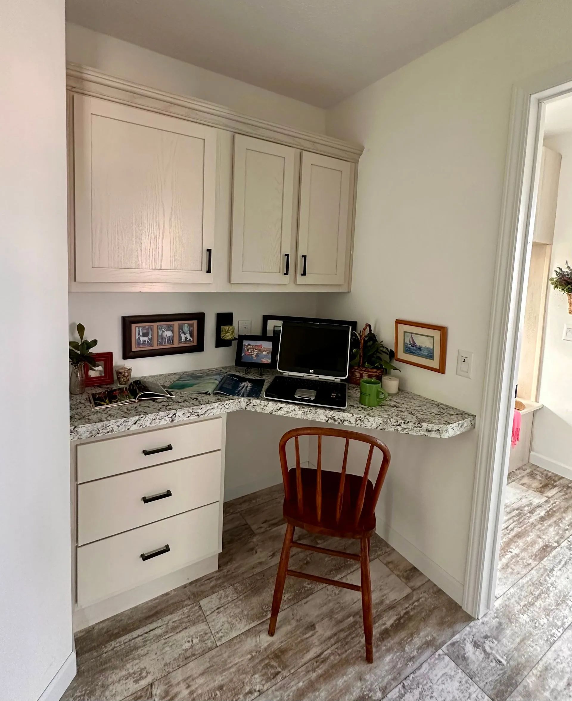 Small home office nook with white cabinets, granite desk, computer, and a red wooden chair