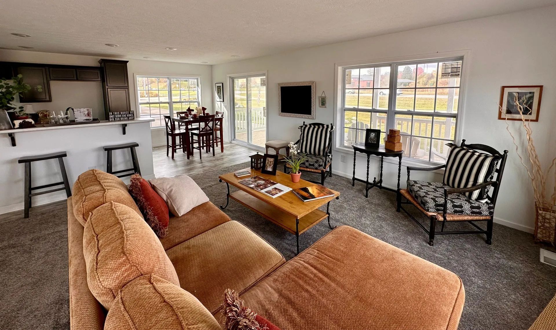Bright living room with tan sofa, coffee table, windows, black chairs, and a small dining area.