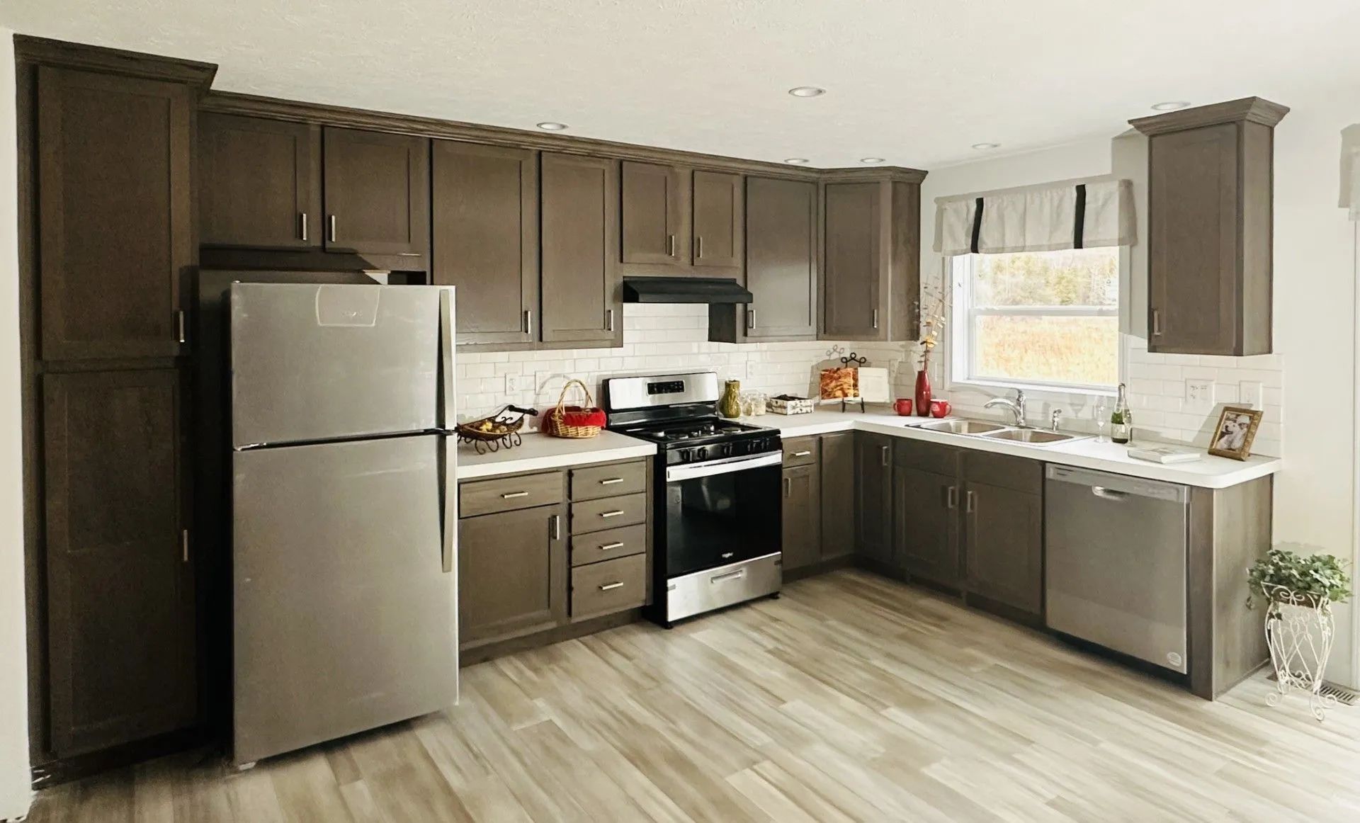 Modern kitchen with stainless steel appliances, dark cabinets, and a window over the sink