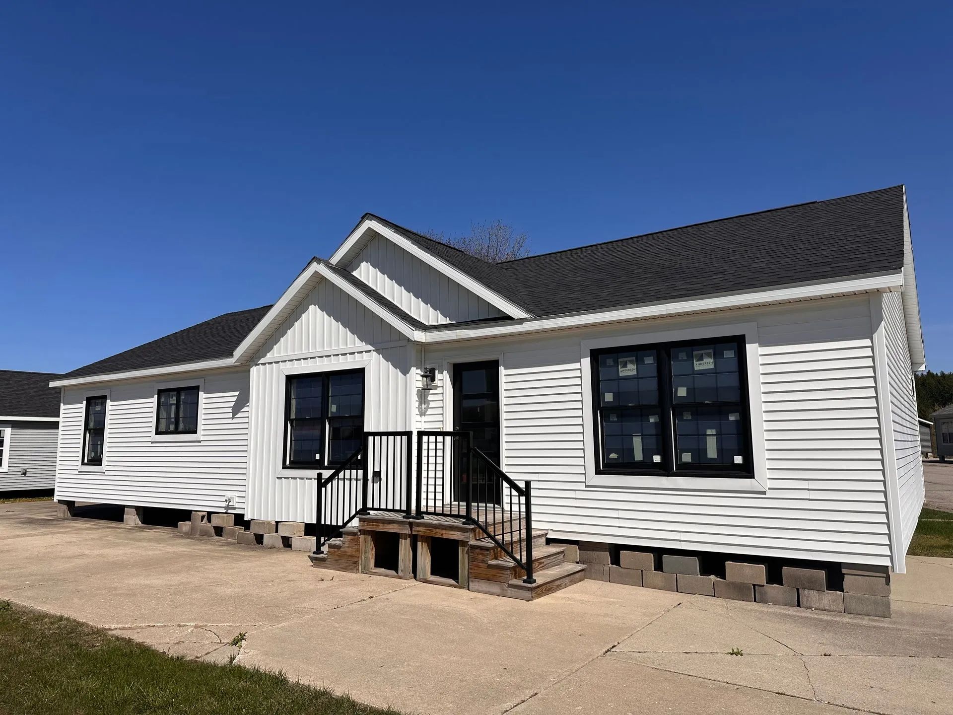 White single-story house with black-trim windows and a small front porch under a clear blue sky