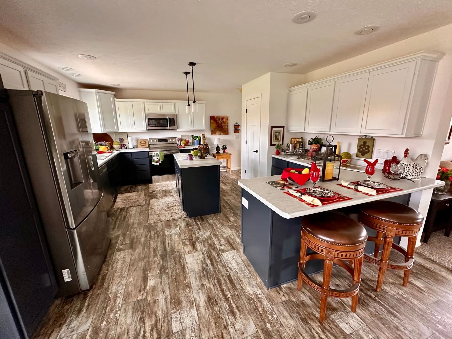 Modern kitchen with white cabinets, dark island, wood floor, and two stools near the counter