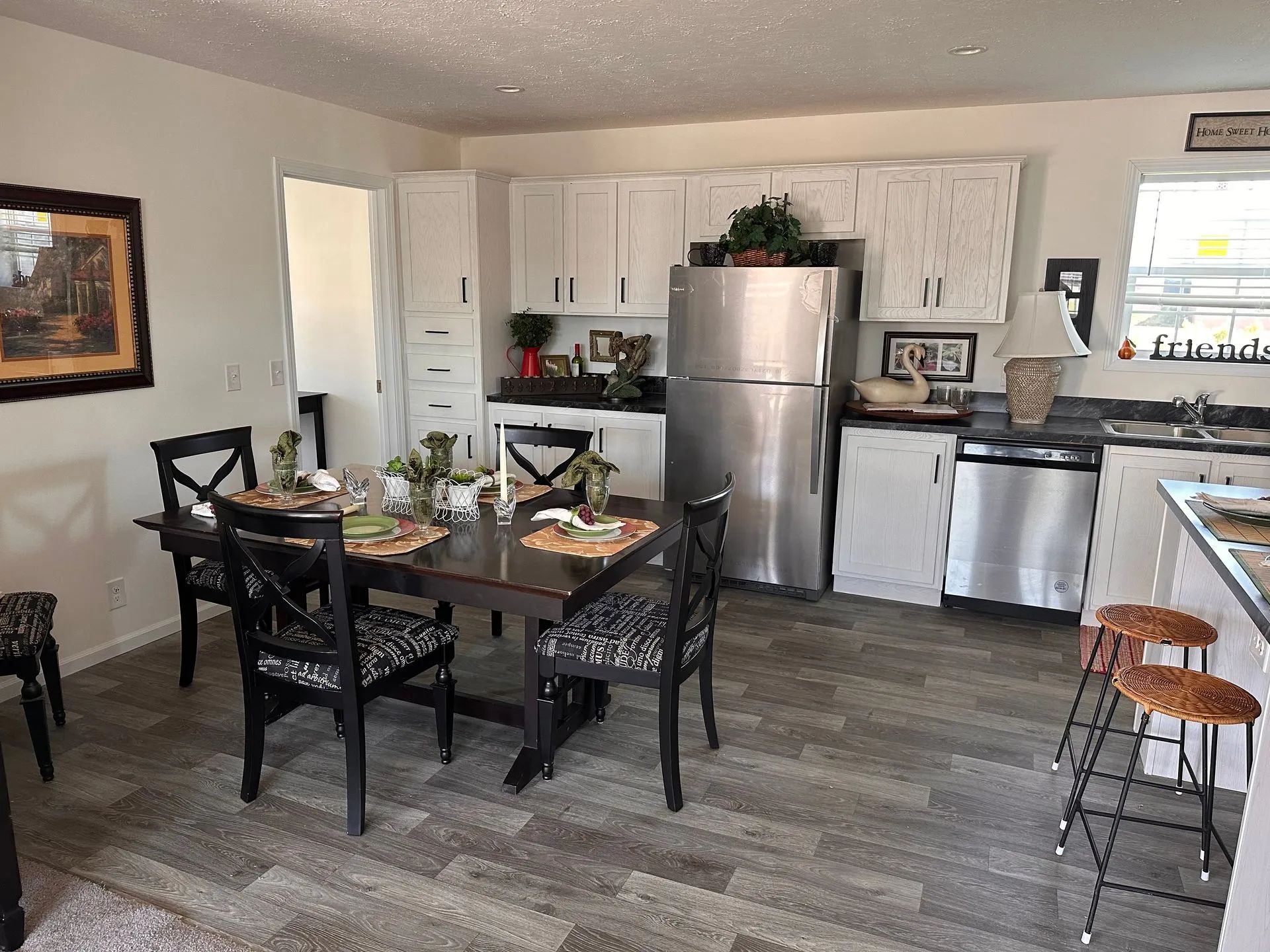 Modern kitchen and dining area with stainless steel appliances, dark wood table, and gray tile flooring