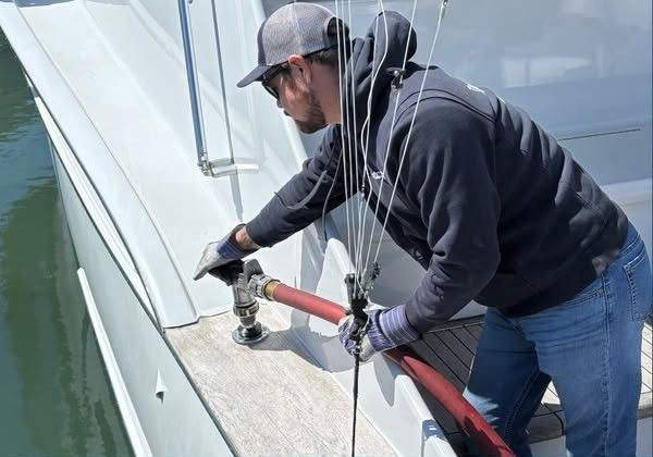 Hands using a wrench to repair an outboard boat motor in sunlight