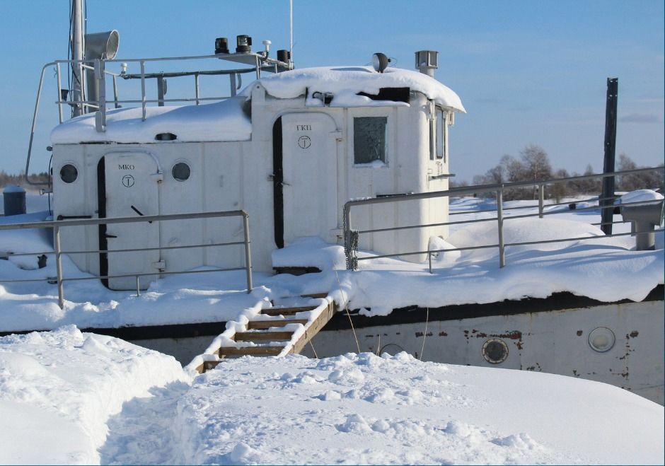 Snow-covered white boat or houseboat docked outdoors in winter