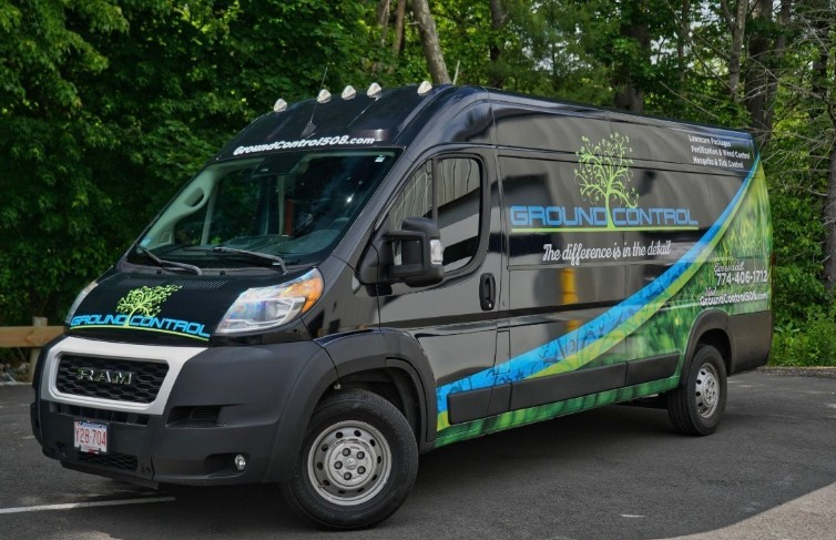 Black Ground Control service van with green and blue graphics parked outdoors.