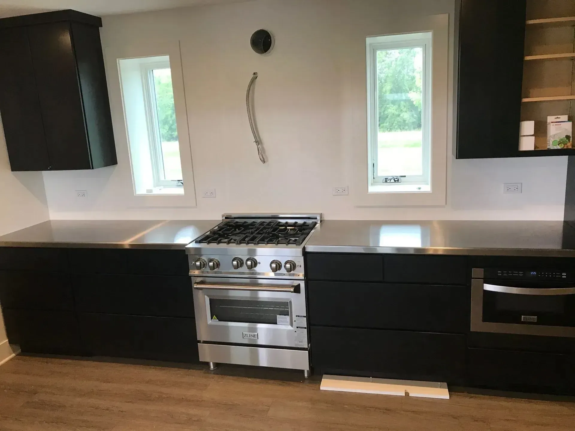 Modern kitchen with black cabinets, stainless steel appliances, and white walls.