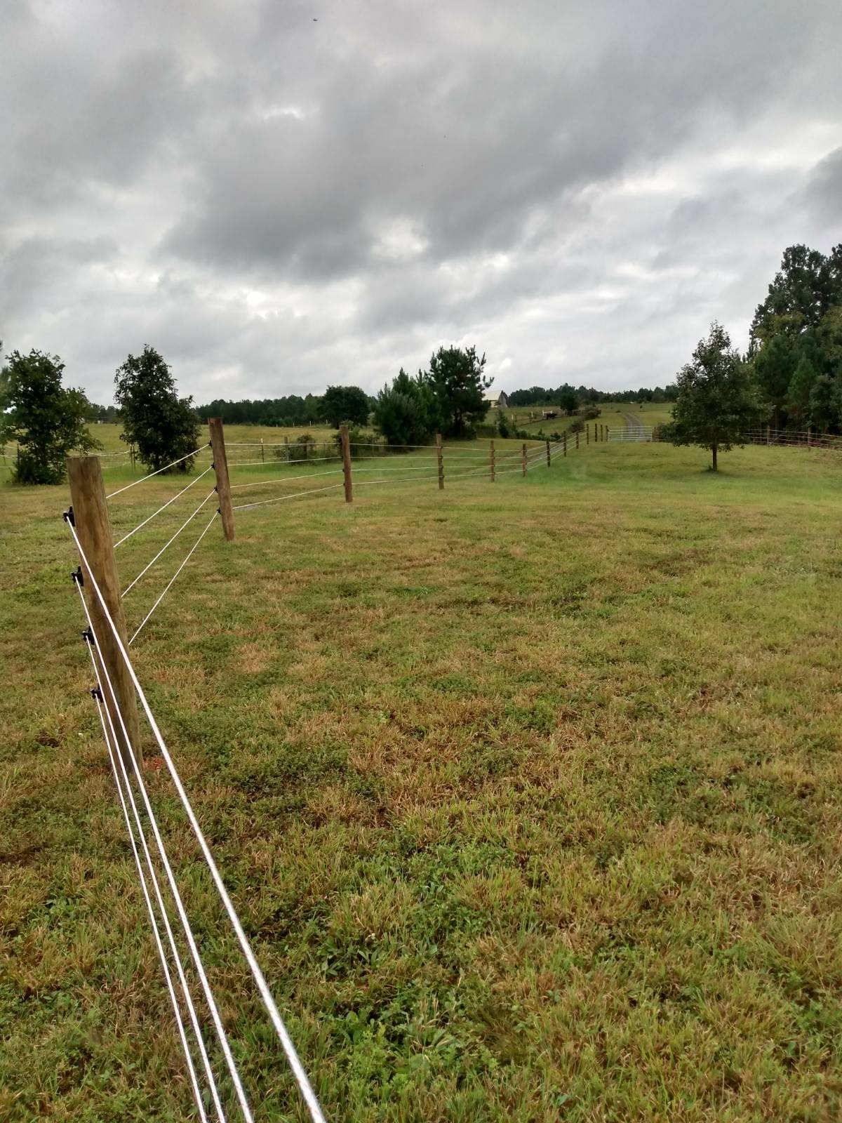 There is a fence in the middle of a grassy field.