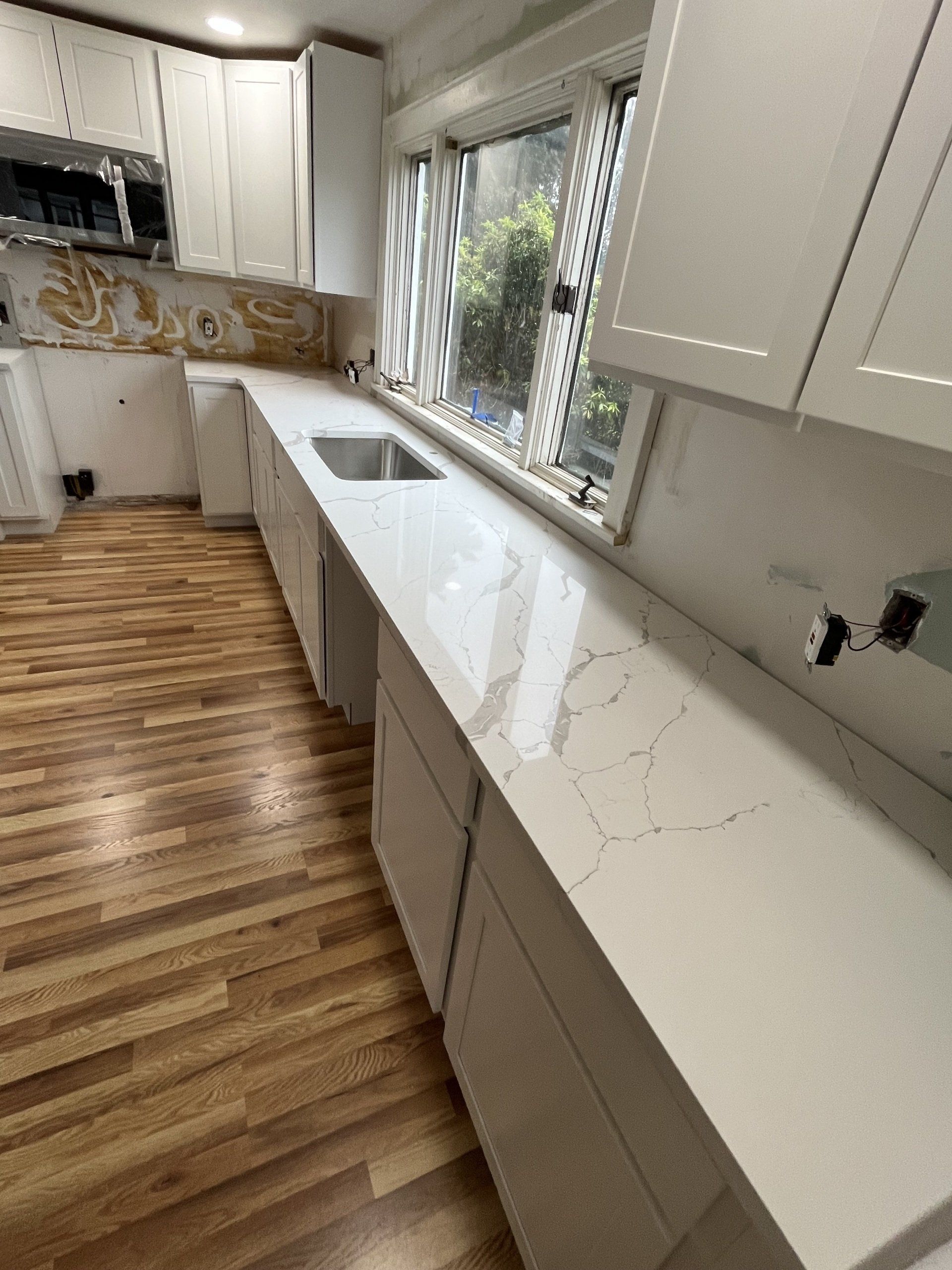 A kitchen with white cabinets, a sink, and a window