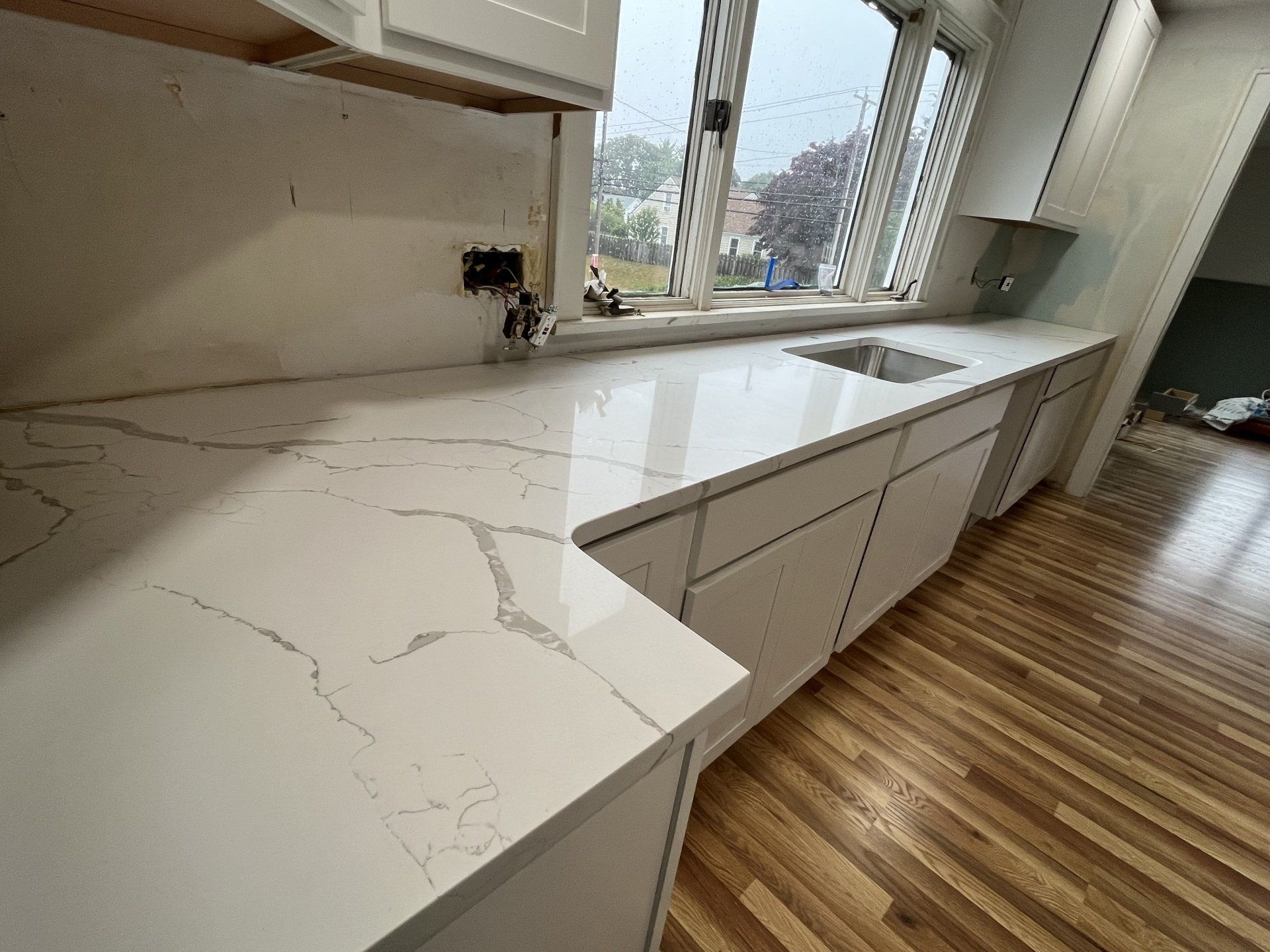 A kitchen with white cabinets, white quartz countertops, and a sink