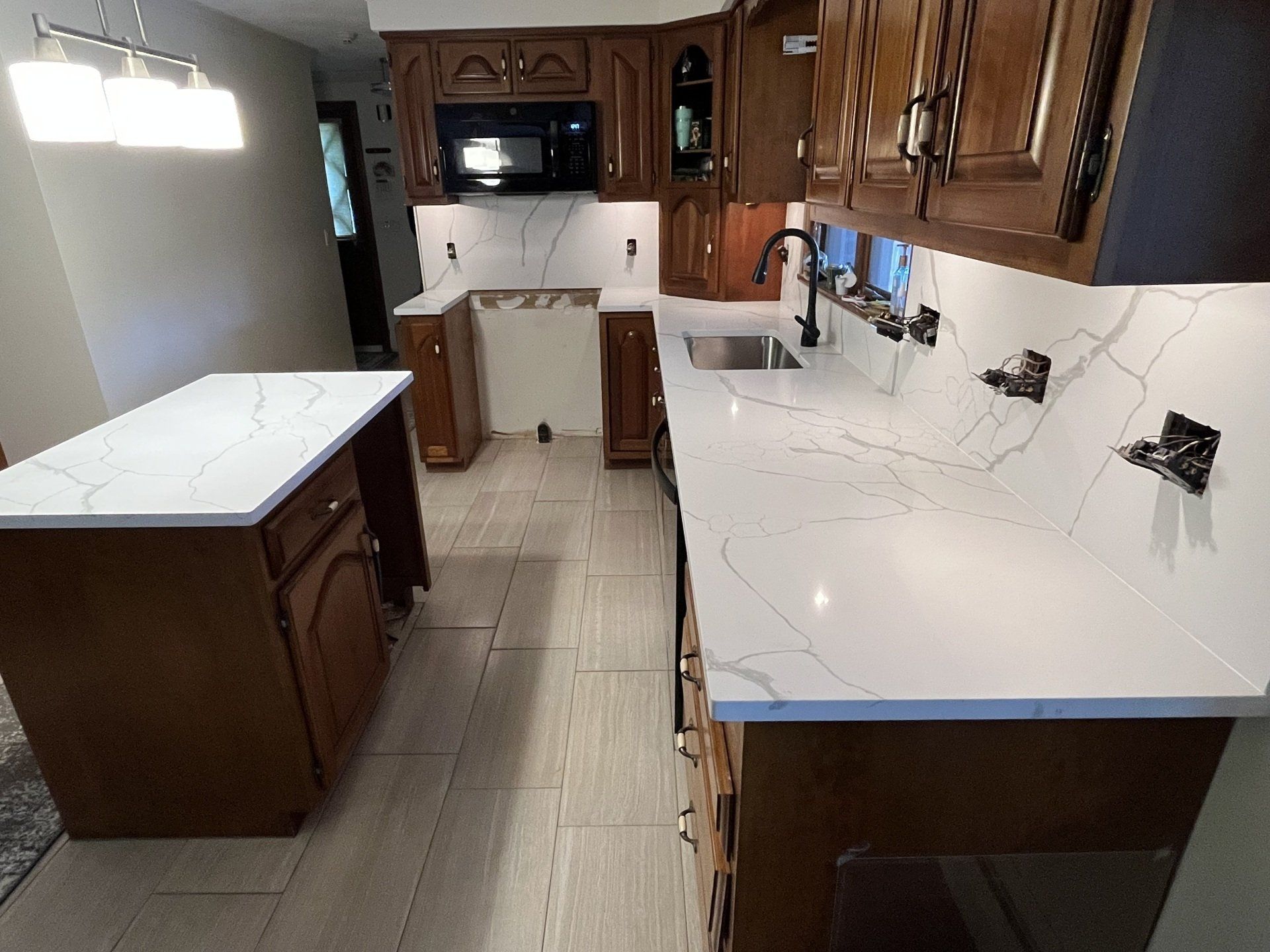 A kitchen with white quartz countertops and wooden cabinets