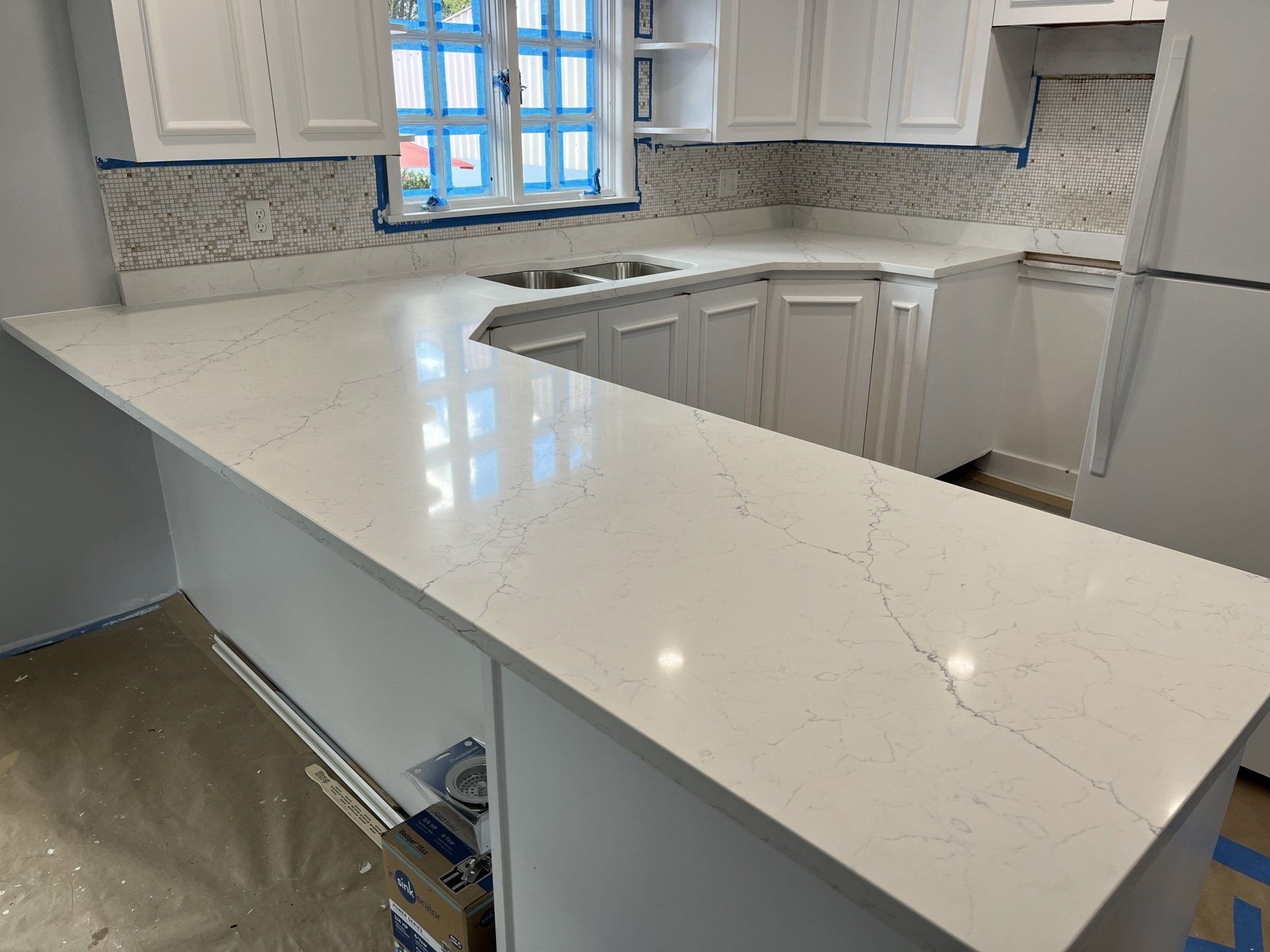 A kitchen with white cabinets and a white quartz countertop