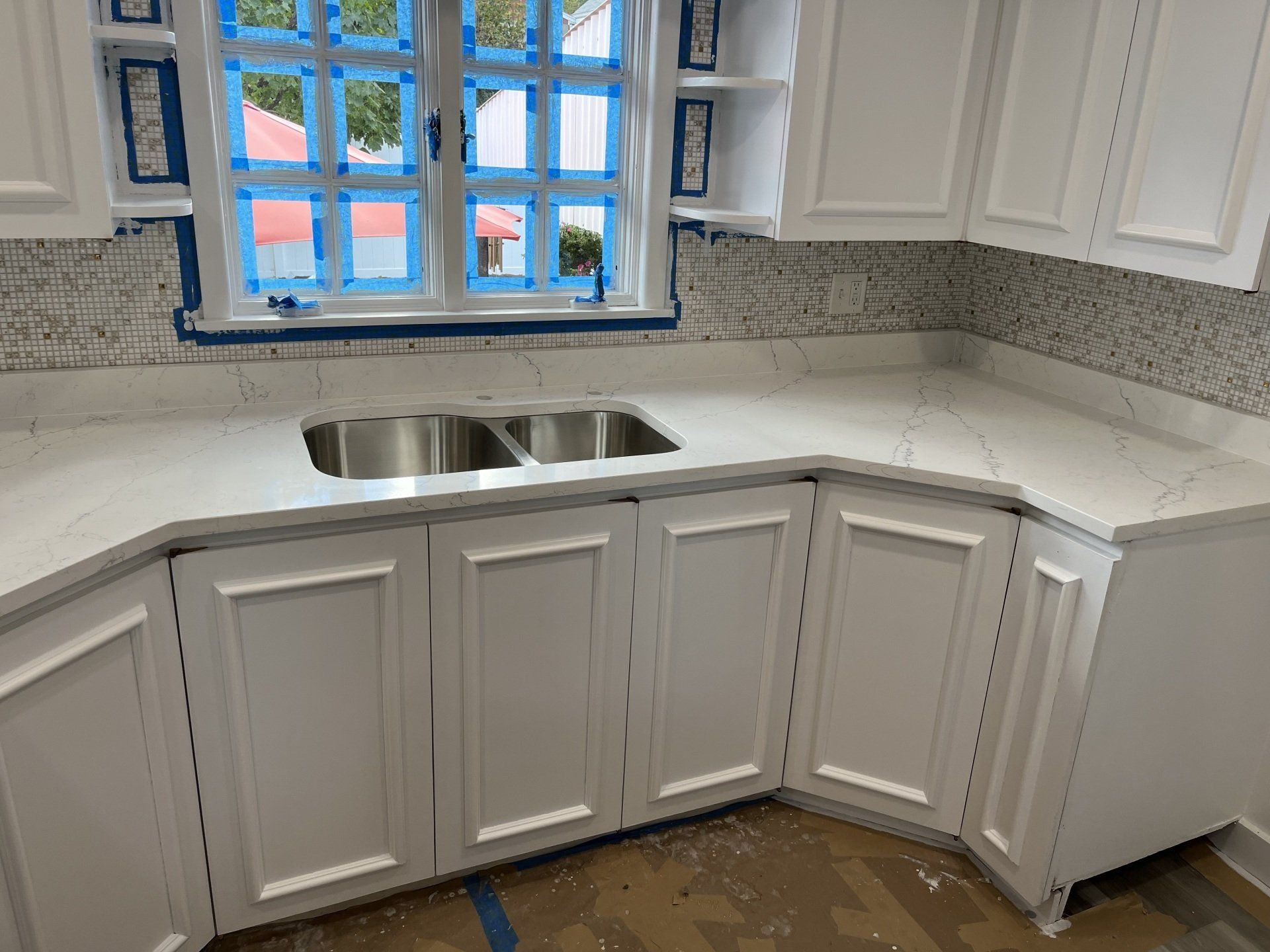 A kitchen with white cabinets and a stainless steel sink