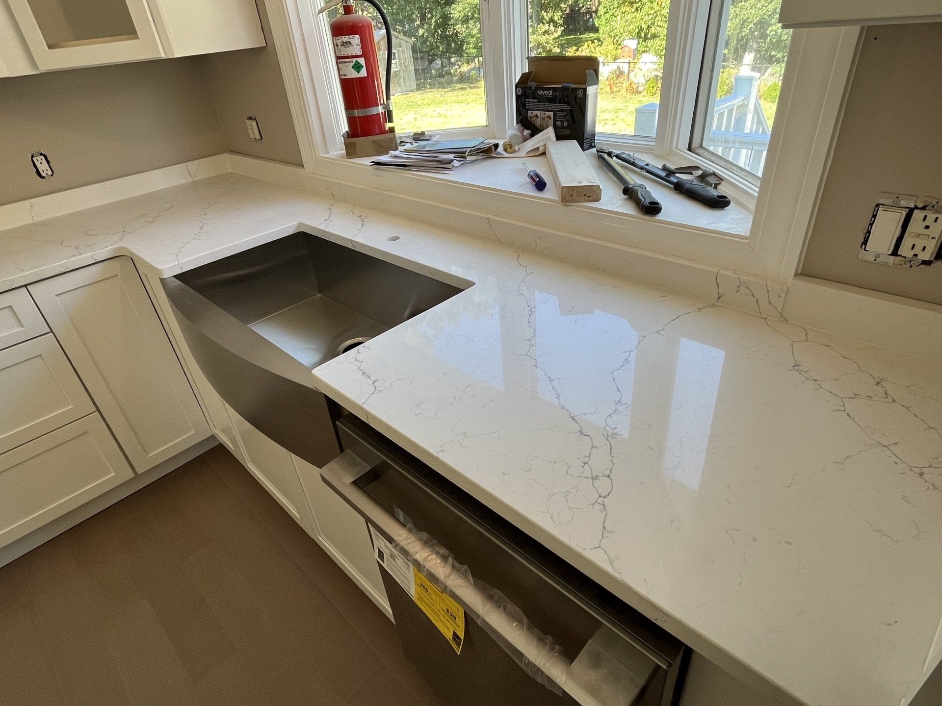 A kitchen with a stainless steel sink and a fire extinguisher on the window sill