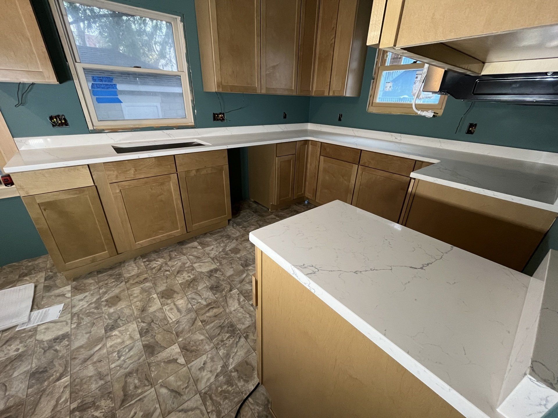 New kitchen with blue-green walls and brown cabinets