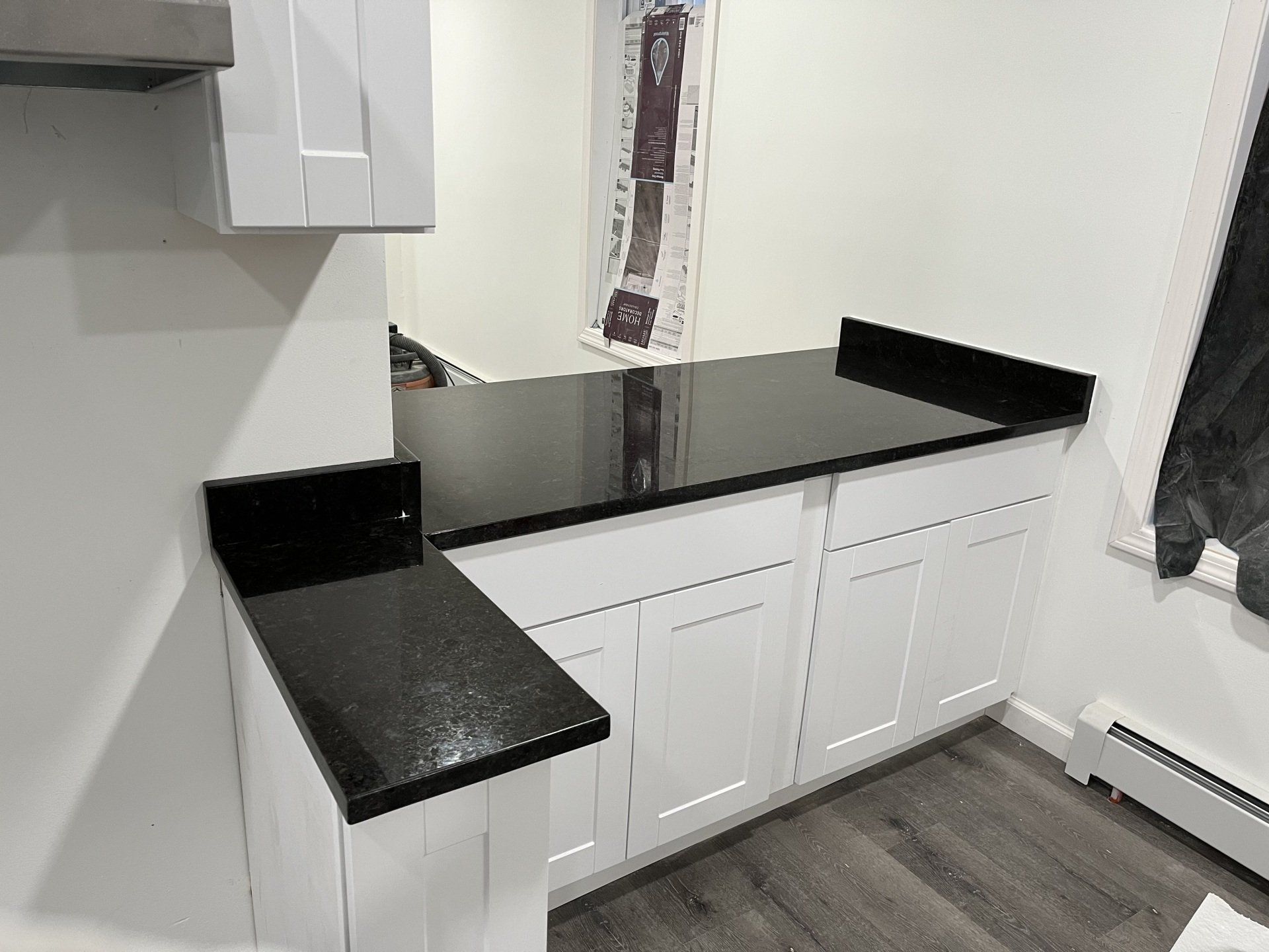 A kitchen with white cabinets and a black countertop