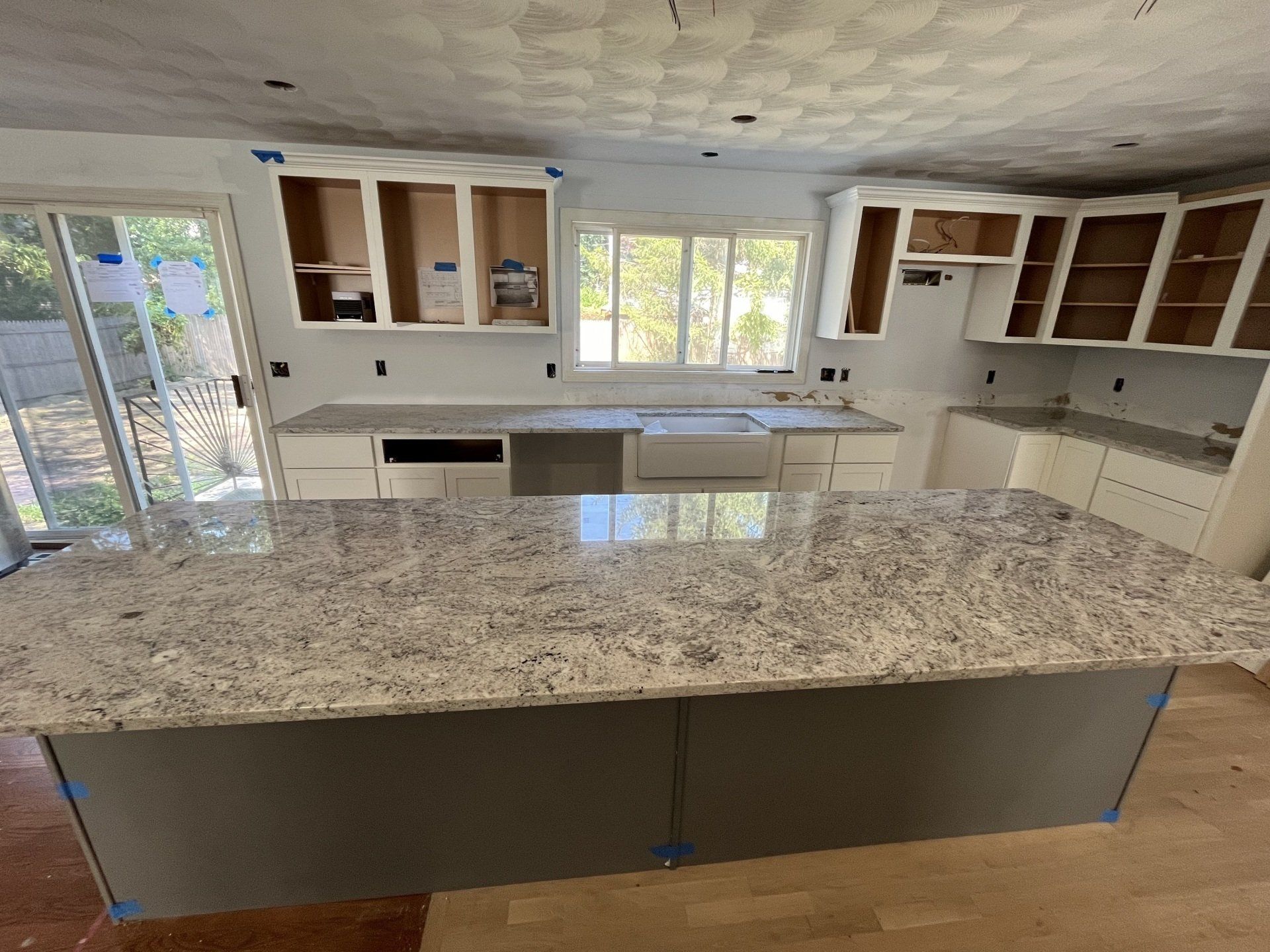A kitchen with granite countertops and white cabinets is being remodeled