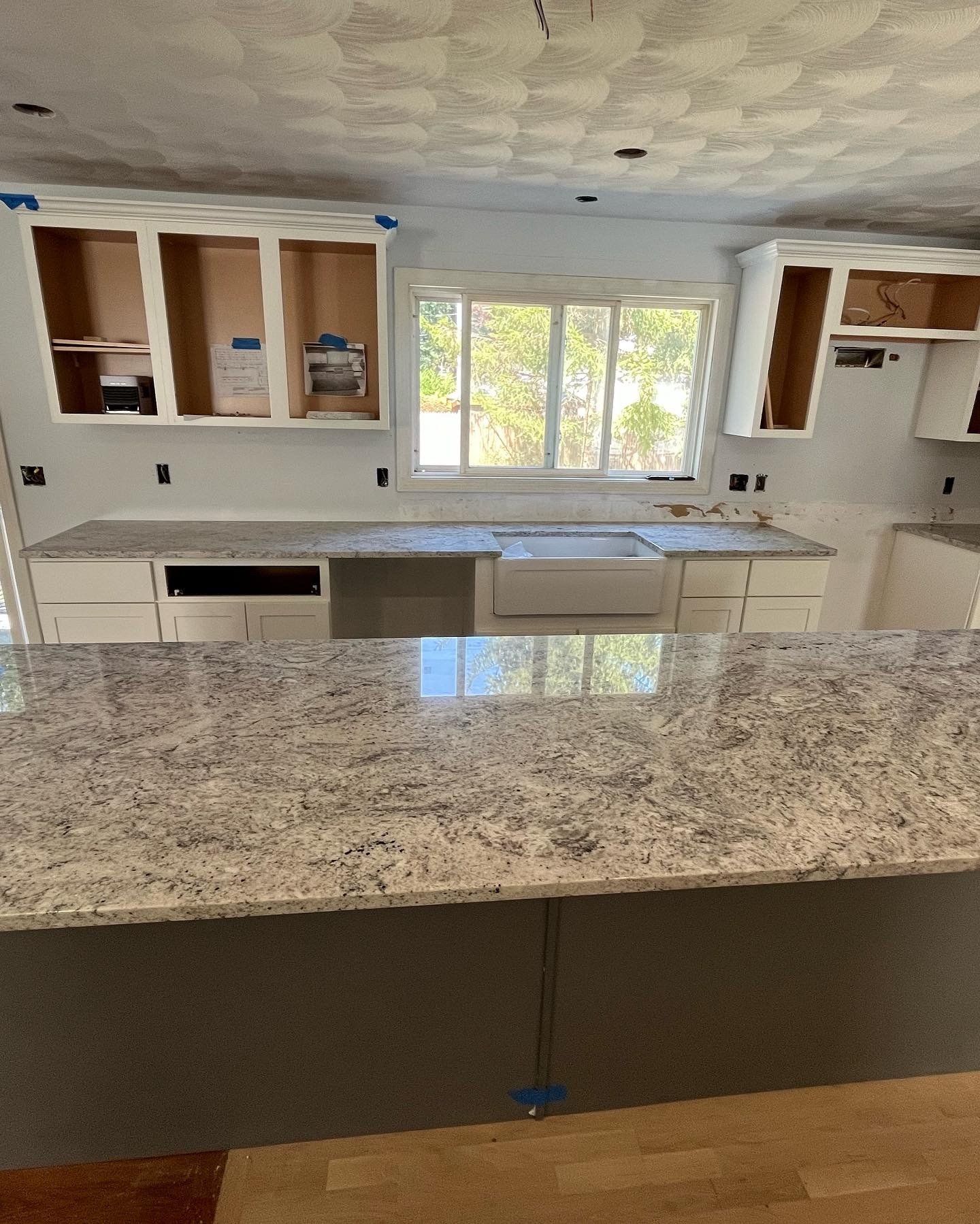 A kitchen with gray and white granite countertops and white cabinets