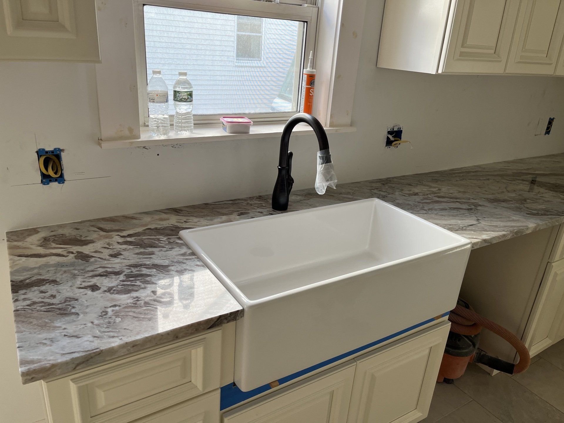A kitchen with a white sink and a black faucet